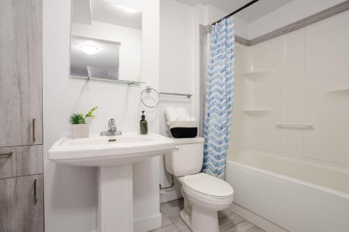 a white bathroom with a toilet and a sink at Amazing 4 Bedroom Unit in Downtown in Montréal