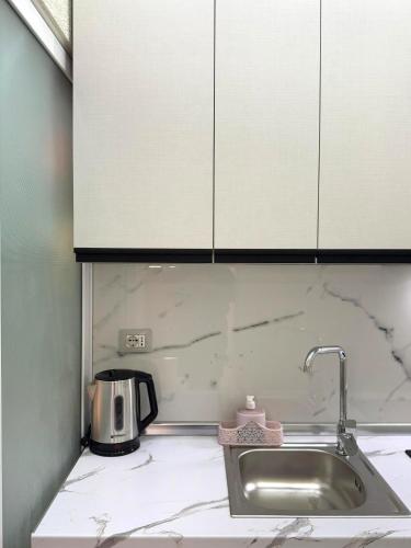 un bancone da cucina con lavello e mobili bianchi di Center Duplex a Vlorë