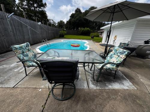 a patio with a table and chairs and an umbrella at Pool House in Broussard