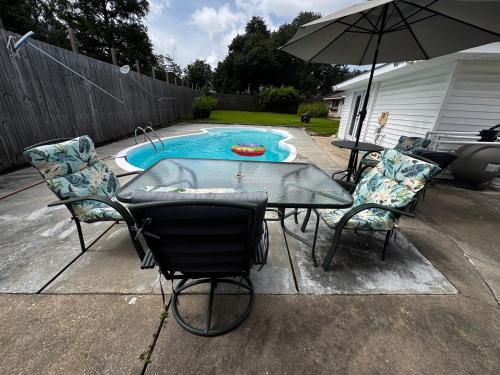 a table and chairs with an umbrella next to a pool at Pool House in Broussard