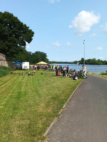 a group of people sitting on the grass near the water at Camp in Horní Počaply