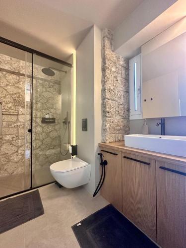 a bathroom with a toilet and a sink and a shower at Linen by Goutos Luxury Living in Kranidi