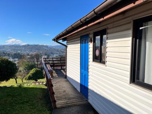 a house with a blue door and a wooden porch at Cabañas Parque Del Lago in Panguipulli