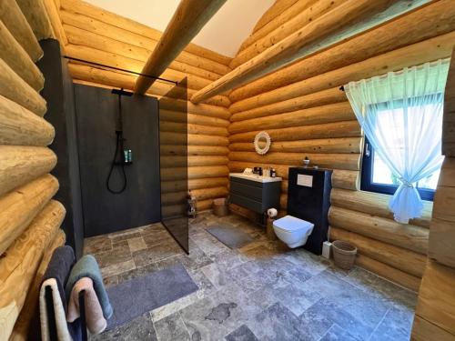 Ein Blockbad mit Toilette und Fenster in der Unterkunft Sub Stele Chalets in Holbav