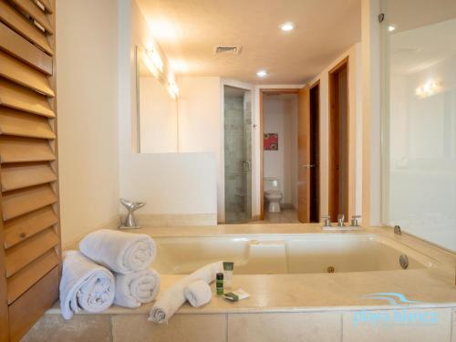a bathroom with a tub with towels and a mirror at Playa Blanca Premier Unit 1302 in San Carlos