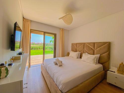 ein Schlafzimmer mit einem großen Bett mit einem großen Fenster in der Unterkunft Luxury Apartment in Prestigia Marrakech in Marrakesch