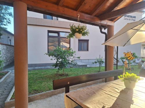 una mesa de madera con una sombrilla en el patio en Apartmani Zara & Duje, en Bibinje