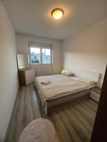 sypialnia z dużym łóżkiem i oknem w obiekcie Sunset Apartment w Prisztinie