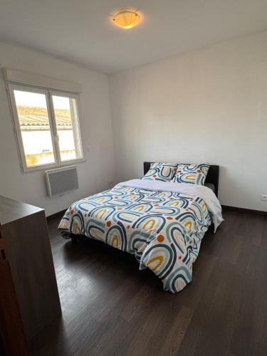 a bedroom with a bed with a colorful comforter and a window at Maison spacieuse et confortable in Fos-sur-Mer