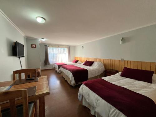 a hotel room with three beds and a table at Cabañas Parque Del Lago in Panguipulli
