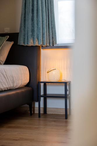 a side table next to a bed and a window at De Weldoeninge in Wingene