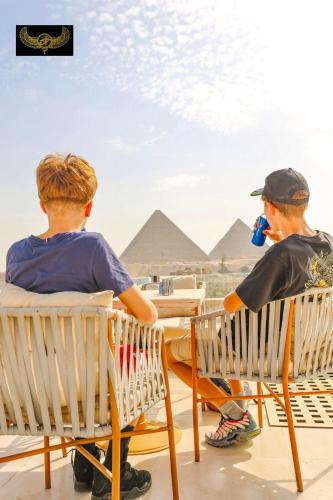 two men sitting in chairs looking at the pyramids at Comfort in Cairo