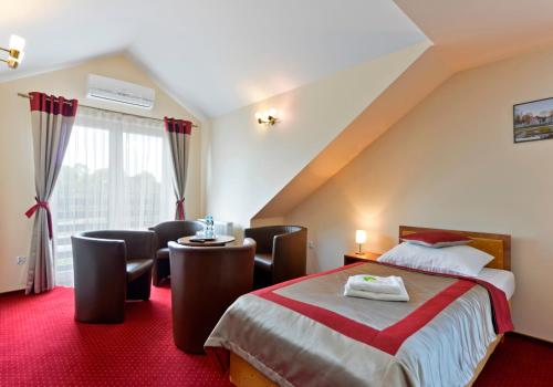 ein Hotelzimmer mit einem Bett und einem Tisch und Stühlen in der Unterkunft Hotel Dukat in Biała Podlaska