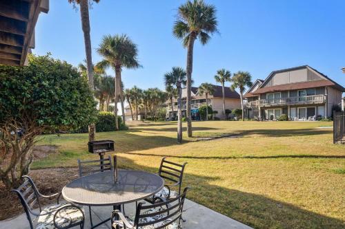 a table and chairs in a yard with palm trees at 327 Capt John Fripp Villa in Fripp Island