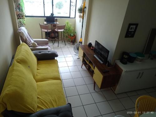 a living room with a yellow couch and a tv at Vista para o mar e Farol de Olinda, Perto da FACULDADE DE MEDICINA DE OLINDA , Cama Solteiro Com colchão Adicional, Estante e Ventilador in Olinda