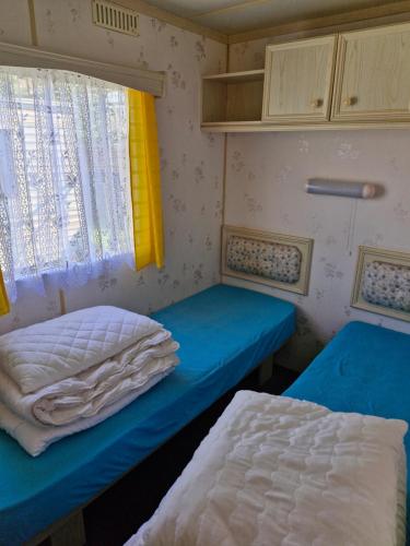 two beds in a small room with a window at Rodzinne Domki Łeba in Łeba