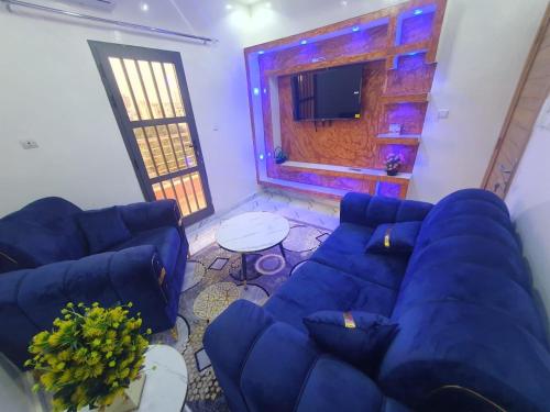 ein Wohnzimmer mit einem blauen Sofa und einem Tisch in der Unterkunft Alouche in Dakar
