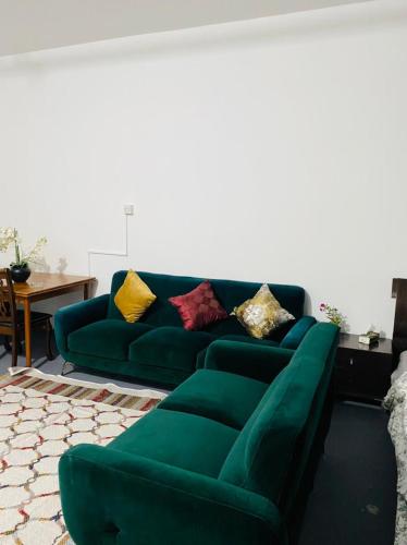 a green couch with colorful pillows in a living room at 1 Bhk in Abu Dhabi