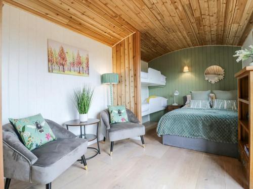 a bedroom with a bed and two chairs in it at Luxury Shepherd Hut with Private Hot Tub in Swaffham Bulbeck