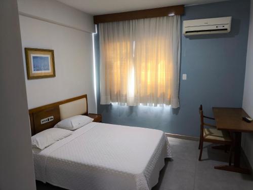 a bedroom with a bed and a desk and a window at Hotel Transcontinental in Ji-Paraná