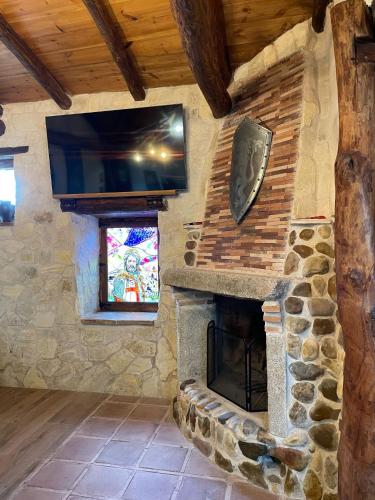 a living room with a stone fireplace and a tv at Casa Los Templarios, cerca de Puy du fou in Burujón