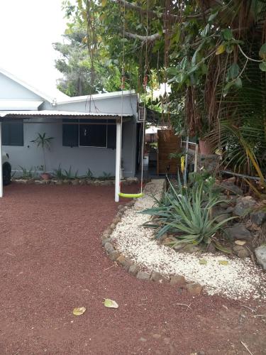 a house with a white roof and a yard at Aloes Lagoon Lodge in Saint-Paul