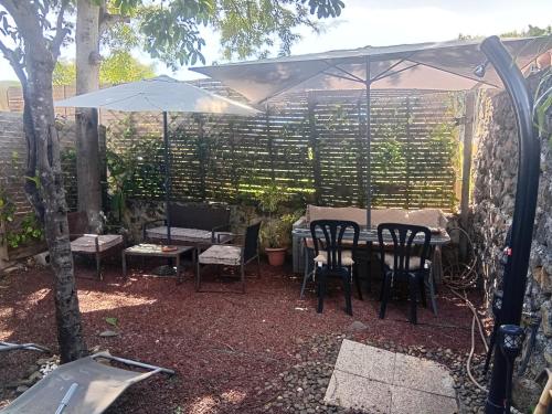 a patio with a table and chairs and an umbrella at Aloes Lagoon Lodge in Saint-Paul