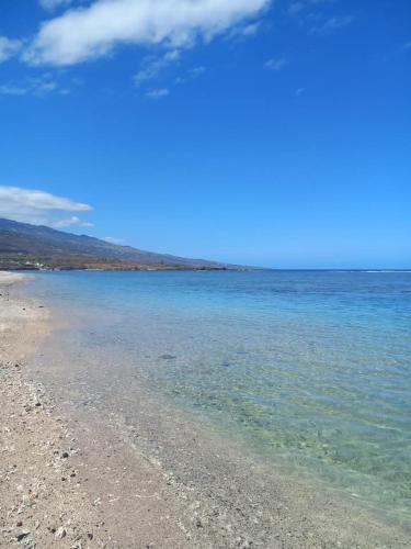 a beach with blue water and a blue sky at Aloes Lagoon Lodge in Saint-Paul