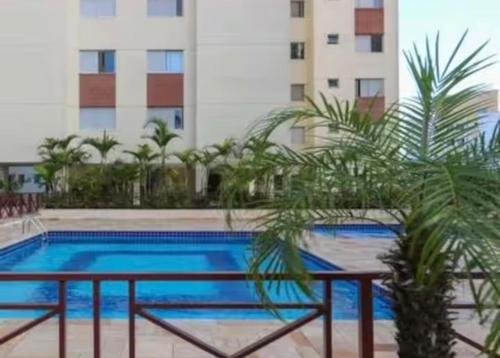 une piscine avec des palmiers devant un immeuble dans l'établissement Morumbi Stadium Apartment, à Água Boa