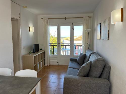 Una sala de estar con un sofá azul y una mesa. en Costa Arenal 112 by SOM Menorca, en Arenal d'en Castell