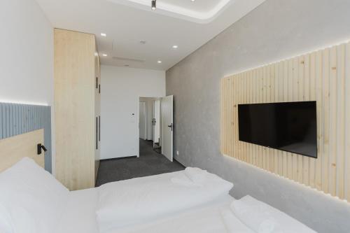 a room with a tv on a wall with white beds at Apartmány Prusinovského in Kroměříž
