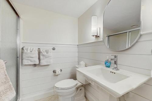 a white bathroom with a sink and a mirror at Saggie Beach Hideaway in Sagamore Beach