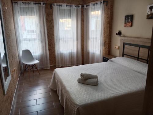 Un dormitorio con una cama y una silla y ventanas. en Apartamento Mercé, en Santa Pola