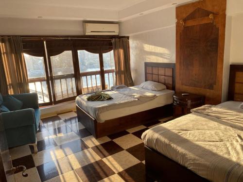 a bedroom with two beds and a chair and windows at Nile sky hotel and suites in Cairo