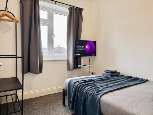 a bedroom with a bed and a flat screen tv at Convenient Private Single Room 30 Min to Central in Wembley