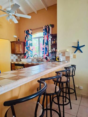 a kitchen with four bar stools at a counter at Luxury Beachfront House with Pool in Palo Grande