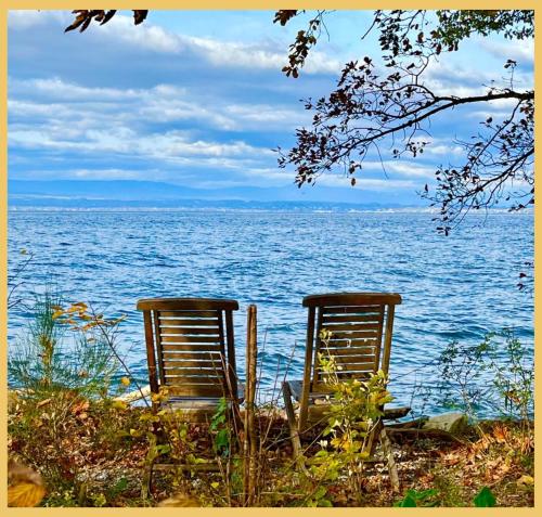 two chairs sitting on the shore of a body of water at La Marina I Maison T4 I Port Ripaille in Thonon-les-Bains