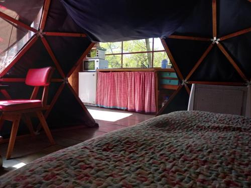 a room with a bed and a chair in a tent at El Domo y La Petaca Delta del Tigre in Tigre