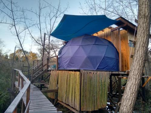 a blue umbrella sitting on top of a wooden fence at El Domo y La Petaca Delta del Tigre in Tigre