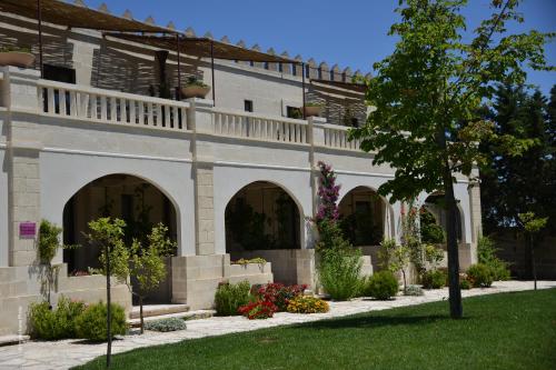 a building with arches and flowers in a yard at Le Scuderie - Castello Monaci in Salice Salentino