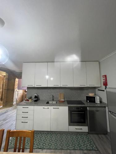 a kitchen with white cabinets and a stove top oven at Casa da Burra in Alijó