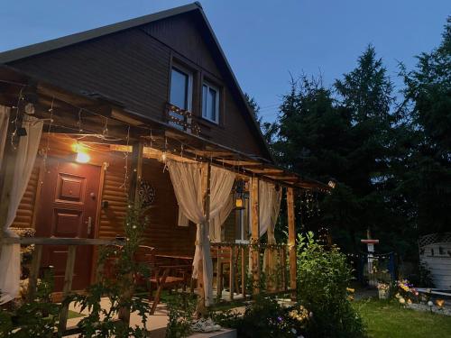 a house with a porch with curtains on it at Ozierański Raj "Pod rzeźbami" in Krynki