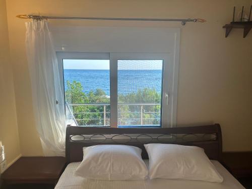 a bedroom with a window with a view of the ocean at Sunnyhomes Vrachos in Vráchos