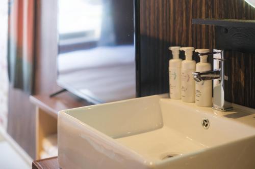 a bathroom sink with a mirror and bottles on it at 泊るHouse千葉駅1分 J - 東京ディズニーランドまで30分 線路傍騒音あり in Chiba