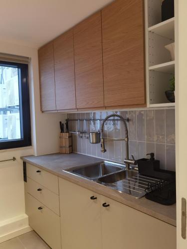 a kitchen with a sink and wooden cabinets at Casa Alegria in Oeiras