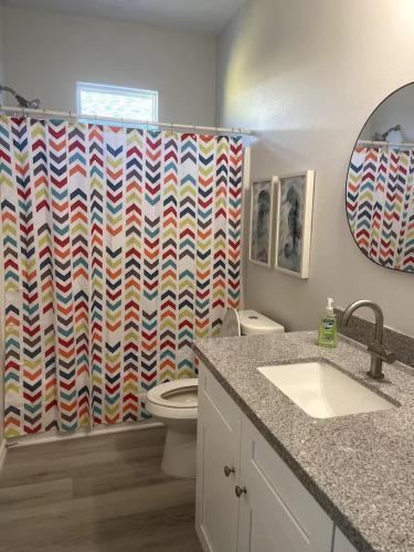 a bathroom with a colorful shower curtain and a toilet at Beachfront Views with 3 bedrooms and 2 bathrooms in Bolivar Peninsula