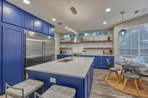a kitchen with blue cabinets and a kitchen island with chairs at The Woodlands Gem with Pool and Spa in The Woodlands