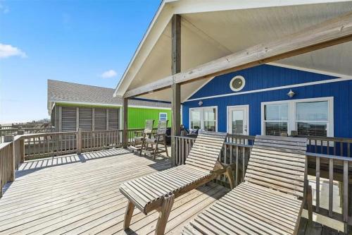 a deck with two benches and a blue building at Beachfront Views with 3 bedrooms and 2 bathrooms in Bolivar Peninsula
