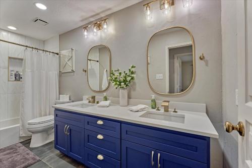 a bathroom with a sink and a toilet and two mirrors at The Woodlands Gem with Pool and Spa in The Woodlands