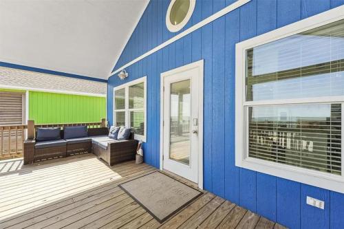 a blue house with a porch with a couch on a deck at Beachfront Views with 3 bedrooms and 2 bathrooms in Bolivar Peninsula